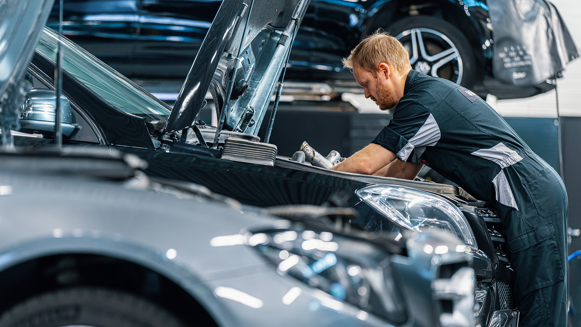 Mercedes-mekaanikko tekemässä huoltoa auton moottoritilaan.